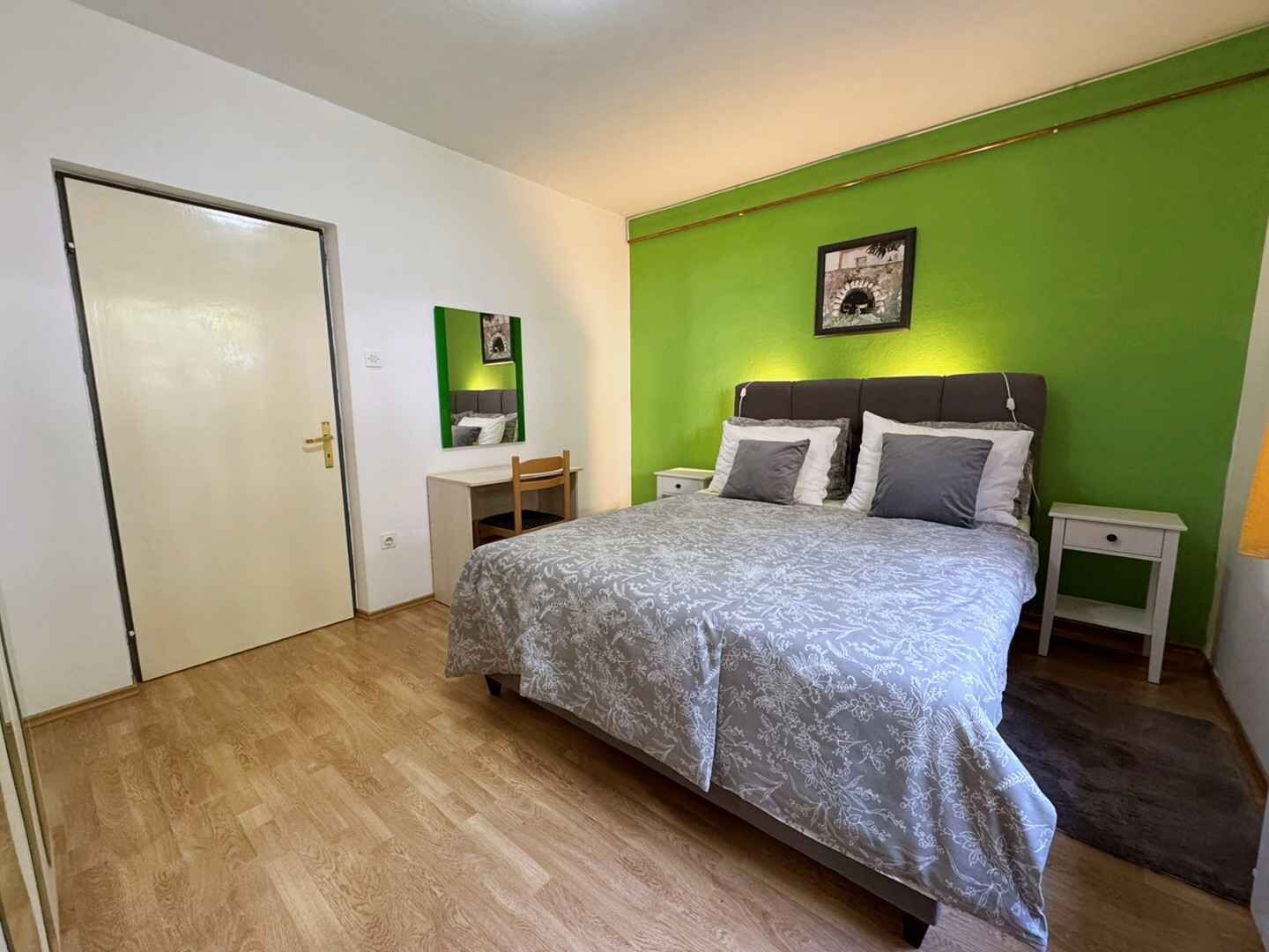 Et soveværelse med en seng, to sengeborde, et skrivebord og en stol.