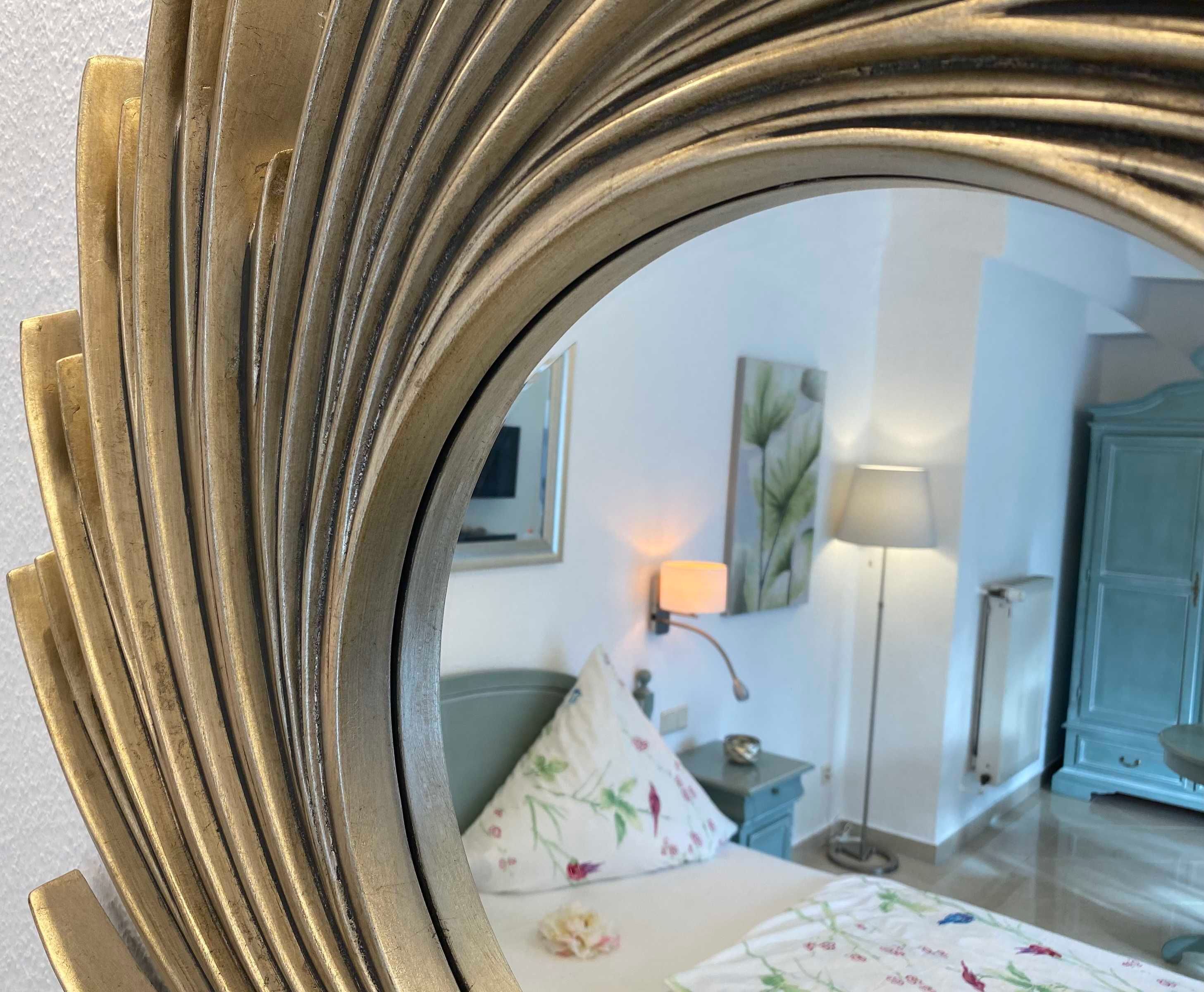 A room with a bed, a nightstand, a lamp, a dresser, and a mirror.