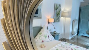 Une chambre avec un lit, une table de chevet, une lampe, une commode et un miroir.