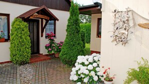 Un bâtiment avec une enseigne en bois, des plantes en pot et une mangeoire à oiseaux fixée au mur.