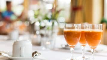 A table with two glasses of orange beverage, a white cup, and a spoon.