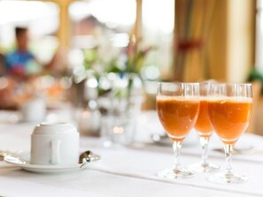 Uma mesa com dois copos de bebida de laranja, uma chávena branca e uma colher.