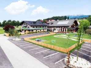 A hotel with a parking lot, a grassy area with a soccer goal, and a mountain in the background. - Double room Aich - Landgasthof Hotel Aichingerwirt *** superior (Keuschen)