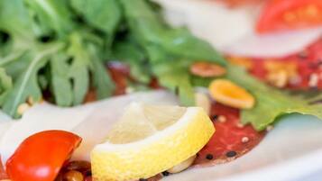 A close-up of a dish with greens, a lemon slice, and a red pepper.