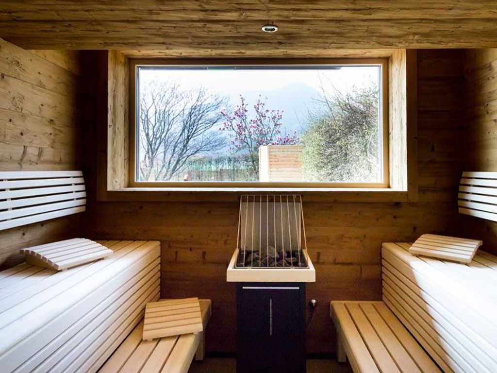 Uma sala de sauna de madeira com bancos e aparelho de sauna.