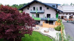 A two-story building with a balcony, a paved patio area with seating, and a well-maintained lawn.
