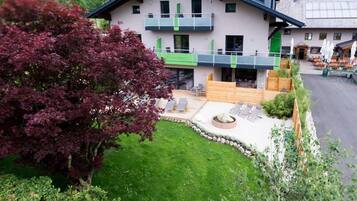 A two-story building with a balcony, a paved patio area with seating, and a well-maintained lawn.