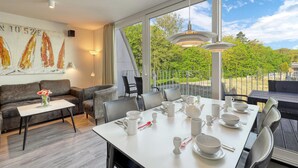 A modern dining area with a large table set for tea, a sofa, and a painting on the wall. - Gorgeous apartment in Travemünde Waterfront with WiFi (Travemünde Waterfront)