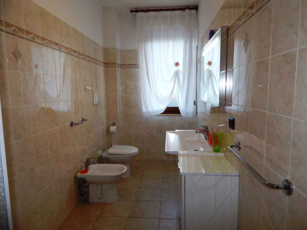 A bathroom with two toilets, a bidet, a sink, and a mirror.
