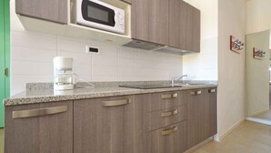 A modern kitchen with grey cabinets, a white microwave, a coffee maker, and a stainless steel sink.