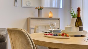Taula de menjador amb un plat de baies, una ampolla de vi i una espelma en un interior modern.