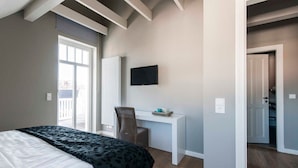 Ein Hotelzimmer mit Bett, Schreibtisch, Stuhl, Fernseher und Blick nach draußen.
