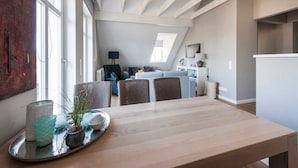 Ein moderner Essbereich mit Holztisch und -stühlen, einer Ablage mit dekorativen Gegenständen und Blick auf eine Küche im Hintergrund.