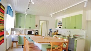 Una cocina con armarios verdes, una mesa de comedor de madera y una cafetera.
