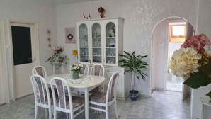 Ein Essbereich mit einem runden Tisch, weißen Stühlen, einer Vitrine und einem Blumentopf.