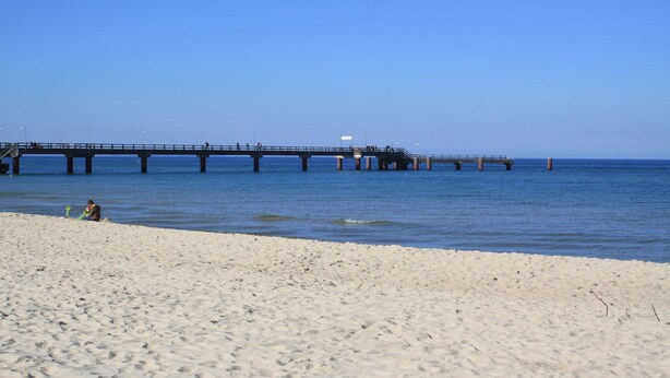 Ein Strand mit einem Steg, der sich ins Wasser erstreckt.