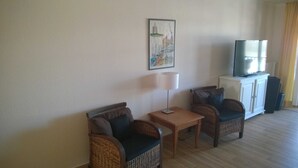 Ein Hotelzimmer mit Korbmöbeln, einem Fernseher auf einem Schrank und einem Bild an der Wand.