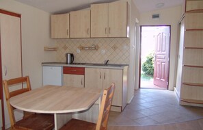 A compact kitchen with wooden cabinets, a dining table, and chairs. - Nice home in Jaroslawiec with WiFi (Jaroslawiec)