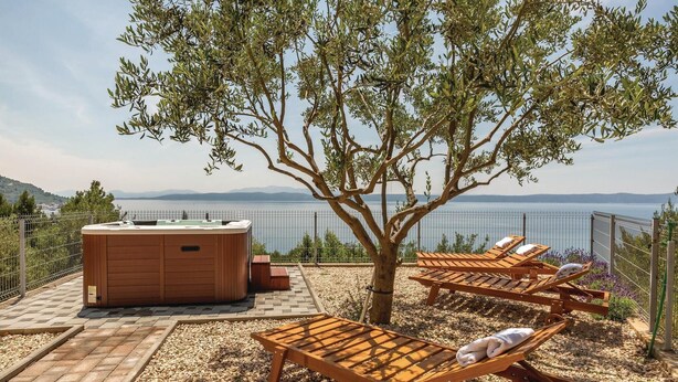 Un bain à remous, des chaises longues en bois et une vue sur un lac.