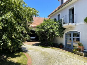 A residential building with a gravel driveway, a covered carport, and a balcony with a metal railing.