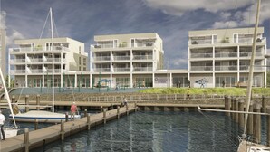 A waterfront property with multiple balconies, a dock, and a building with a sign reading "St. Seestastic Priwall". - Priwallpromenade 29, Whg 17 (Travemünde Waterfront)