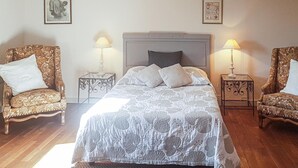 A bedroom with a bed, two chairs, two nightstands, and two wall-mounted lamps. - Cozy home in Plogastel St Germain with WiFi (Plogastel St Germain)