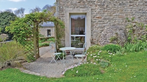 A stone building with a garden patio featuring metal chairs and a table. - Cozy home in Plogastel St Germain with WiFi (Plogastel St Germain)