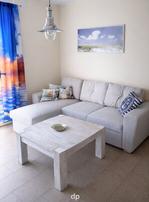 A living room with a grey sofa, a wooden coffee table, a hanging light fixture, and a painting on the wall.