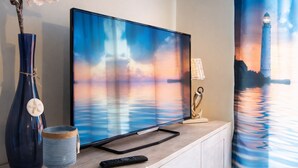 A flat-screen TV on a wooden cabinet with a remote control beside it.