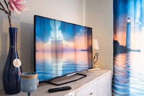 Ein Flachbildfernseher auf einer Holzkommode, daneben eine Fernbedienung.