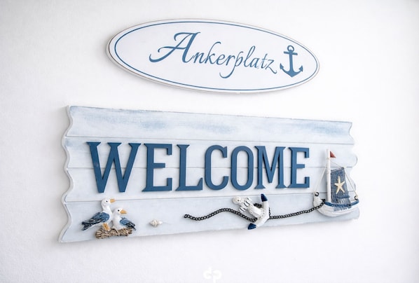 A welcome sign with decorative elements including birds and a sailboat.
