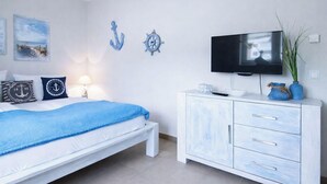 A bedroom with a bed, a TV, a dresser, and nautical-themed decor.