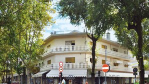 A two-story building with balconies, a cobblestone street, and a parked car. - Holiday apartment with air conditioning and balcony (Bibione)