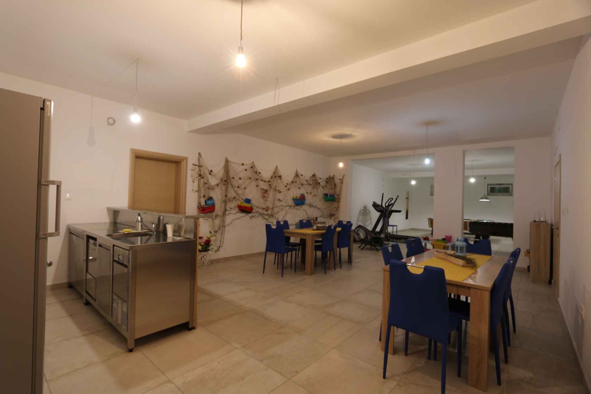 Un'ampia cucina con zona pranzo, caratterizzata da una grande isola, sedie e una decorazione a parete.