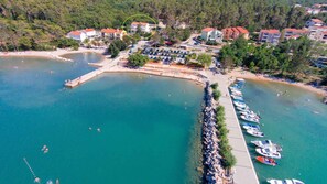 An aerial view of a coastal area with a marina, beach, and residential buildings.