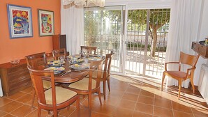 Un coin repas avec une table dressée pour quatre personnes, entourée de chaises en bois dotées d’assises rembourrées. Deux œuvres d’art encadrées sont accrochées au mur au-dessus de la table.