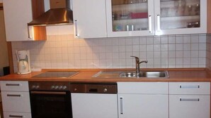A kitchen with white cabinets, a stainless steel range hood, a dishwasher, and a sink.