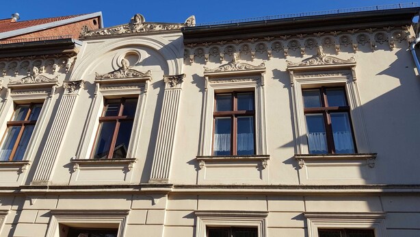 A building with classical architecture, featuring ornate window frames and decorative moldings.