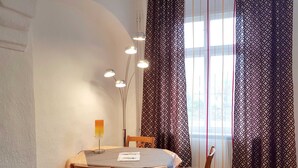 A dining area with a table, chairs, a lamp, and patterned curtains.
