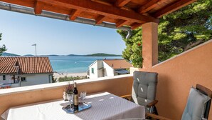 A balcony with a table set for two, overlooking a beach and sea. - Lovely apartment in Jadrija with WiFi (Jadrija)