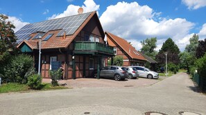 A traditional building with a sloped roof, solar panels, and a car parked in front.