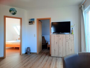 A modern room with a bed, a desk, a television, and a wardrobe.