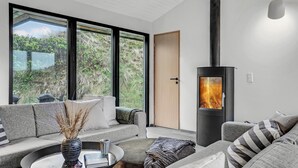 Una sala de estar moderna con un ventanal grande, un sofá, una mesa de centro y un hogar a leña.