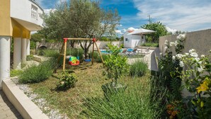 Un jardín residencial con un columpio, una piscina pequeña y un edificio blanco.