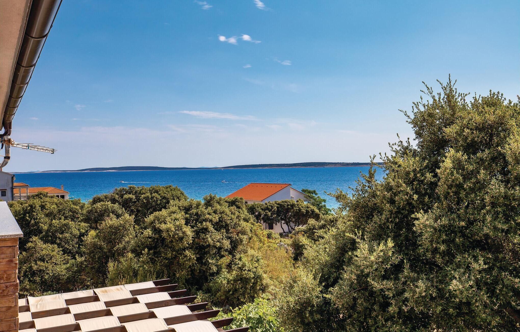 Küstensicht mit blauem Himmel, Wasser und üppigem Grün.