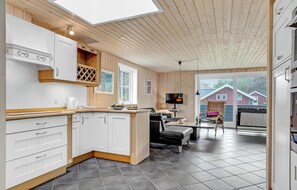 A modern kitchen with white cabinets, a wooden ceiling, and a large window. - Beach front home in Hvide Sande with sauna (Hvide Sande)