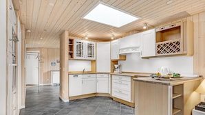 A modern kitchen with wooden cabinets, a central island, and a skylight. - Beach front home in Hvide Sande with sauna (Hvide Sande)