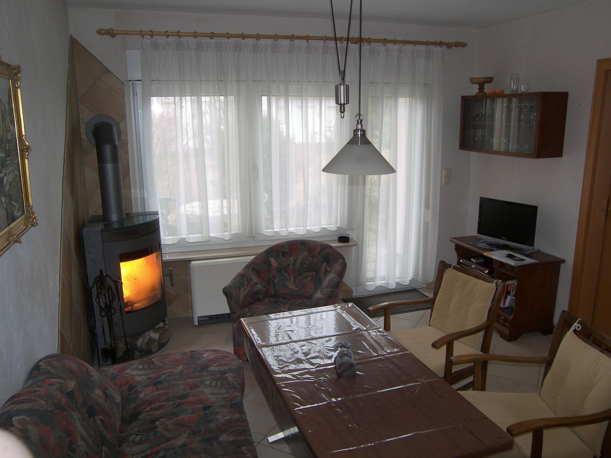 Ett vardagsrum med en öppen spis, en tv och ett matbord.