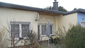 A residential building with a satellite dish, a chimney, and a patio area with a table and an umbrella.
