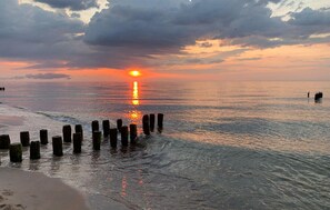A beach at sunset with calm waters and wooden posts in the foreground. - 2 bedroom lovely home in Mielno (Mielno)
